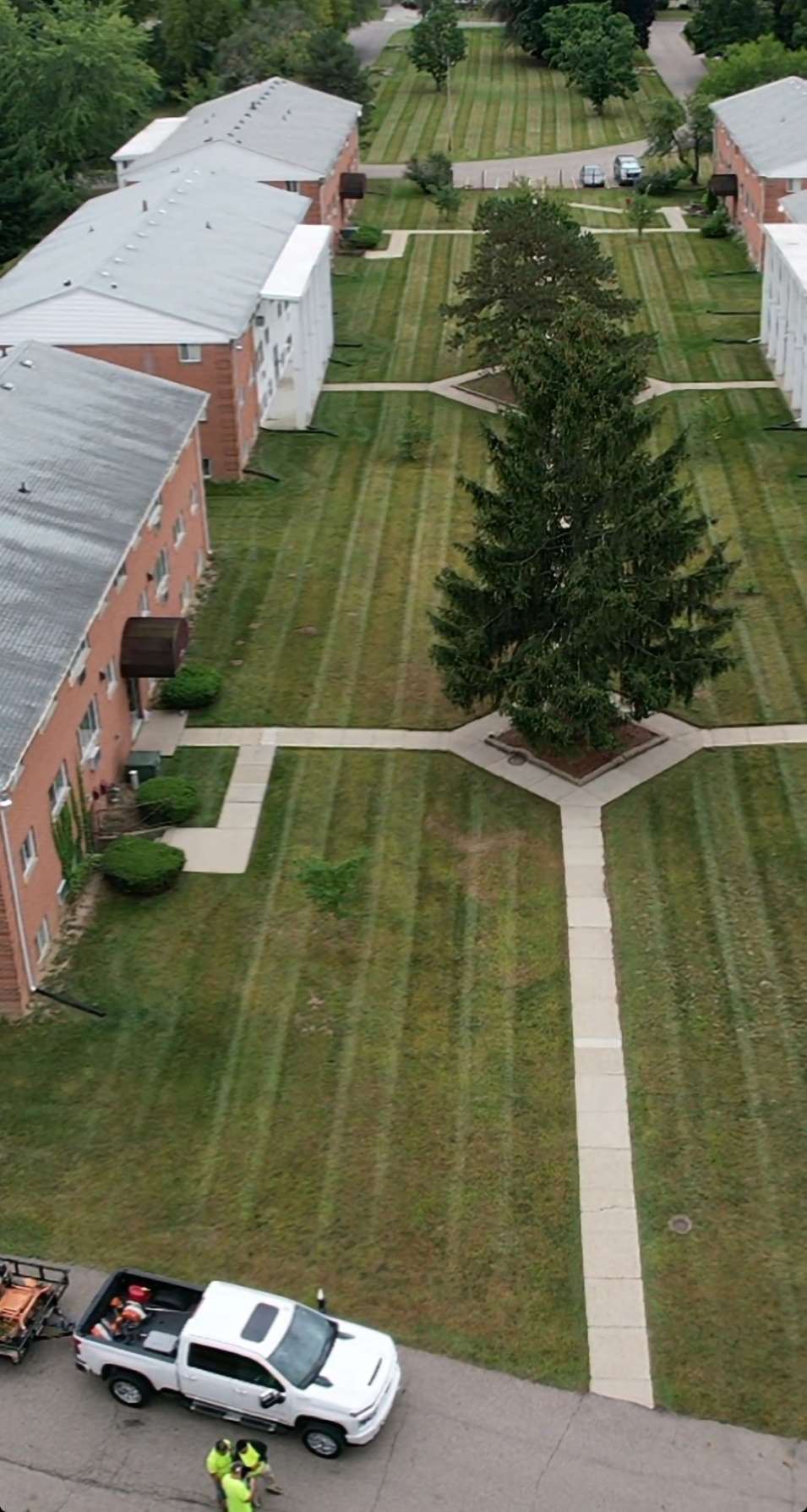 Drone view of a brick apartment complex with freshly striped courtyard lawns