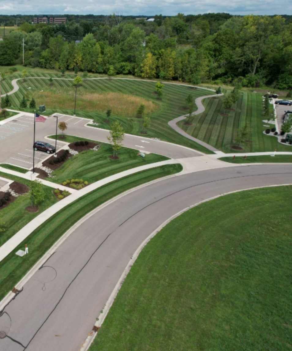 Drone view of a freshly striped lawn, curving path and mulched islands at an office park